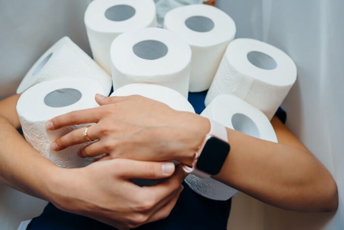 A woman holds many rolls of toilet paper