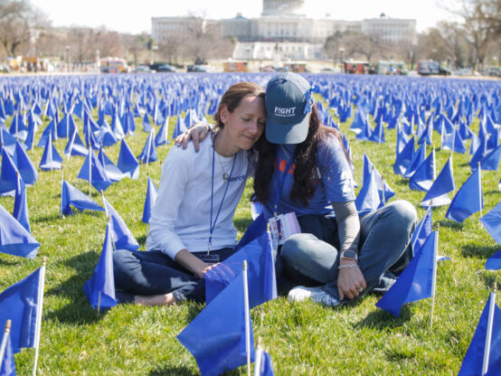 Carole Motycka and Jen Ganser United in Blue Sitting in flag rows in front of Capitol Advocacy in Action