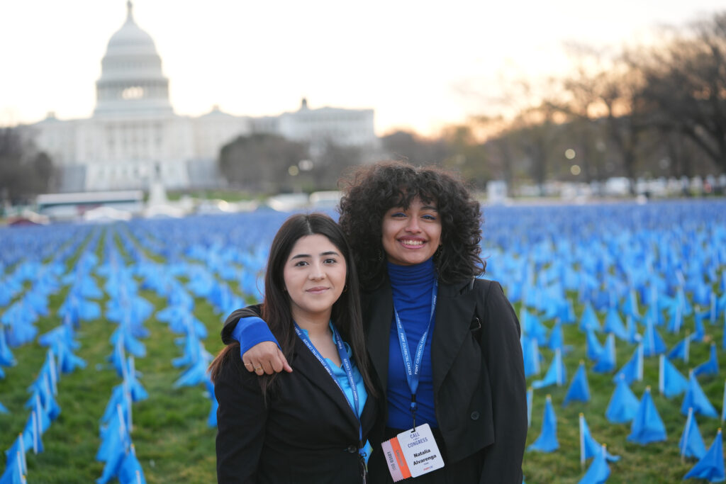 Two advocates standing together in front of the U.S. Capitol during Fight CRC’s Call-on-Congress blue flag installation.